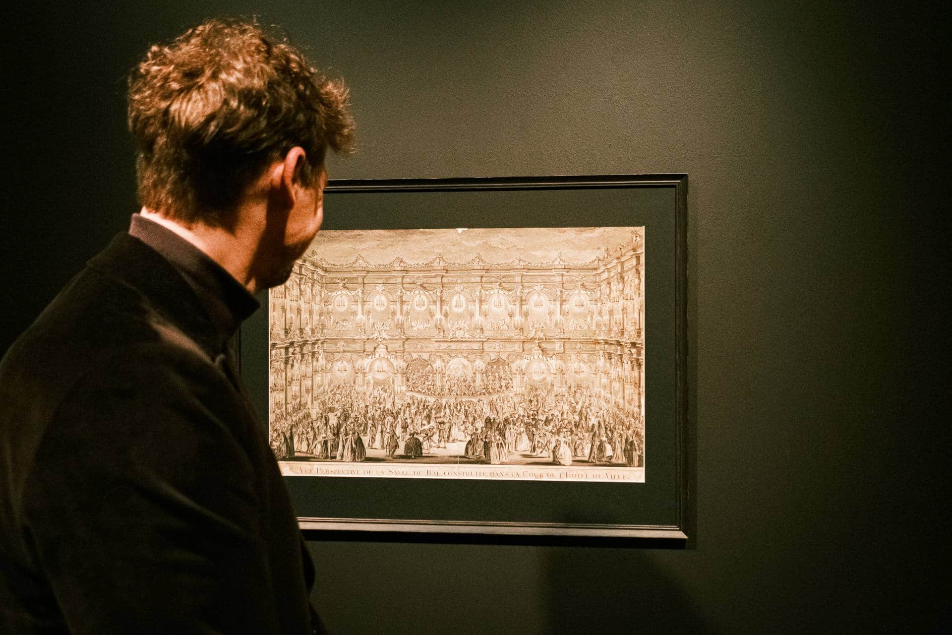 Tartu Ülikooli uus näitus Voltaire, ajalootegija. Pilti vaatab meesterahvas, kes on seljaga