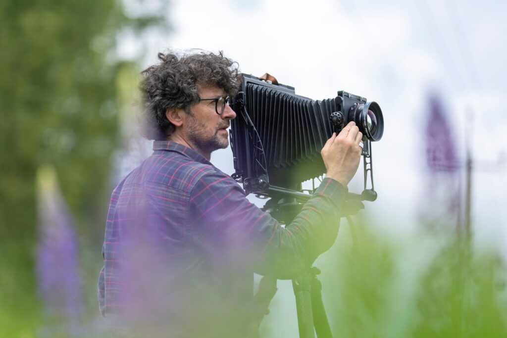 Looduses meesterahvas pildistamas vanaaegse kaameraga. Tegemist on Luca Berti fotoraamatu esitlusega