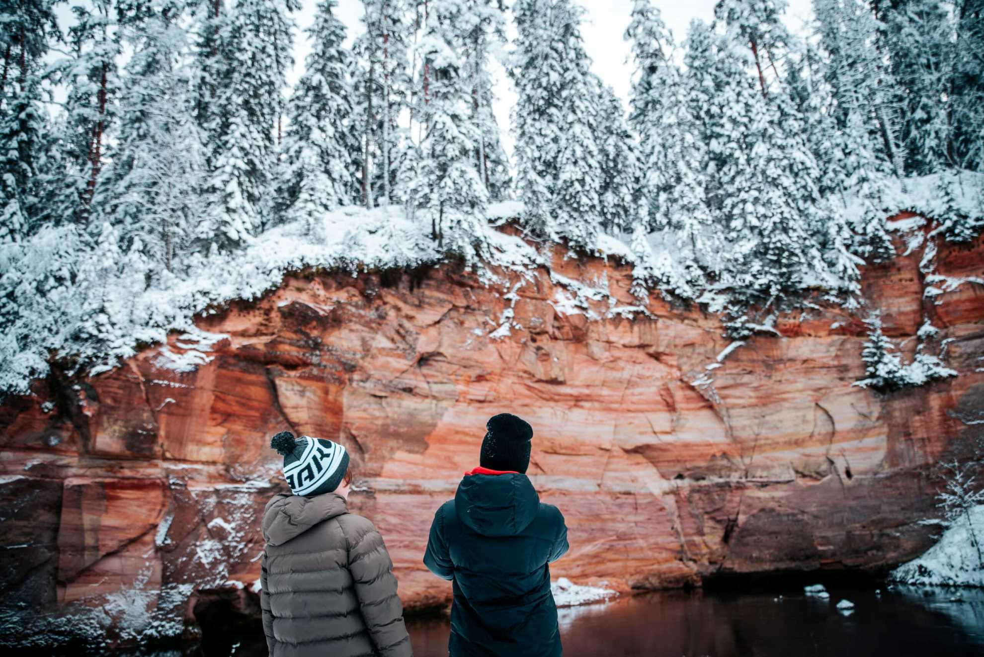 Kaks inimest vaatamas talvist Taevaskoja liivakivipaljandit lumises metsas