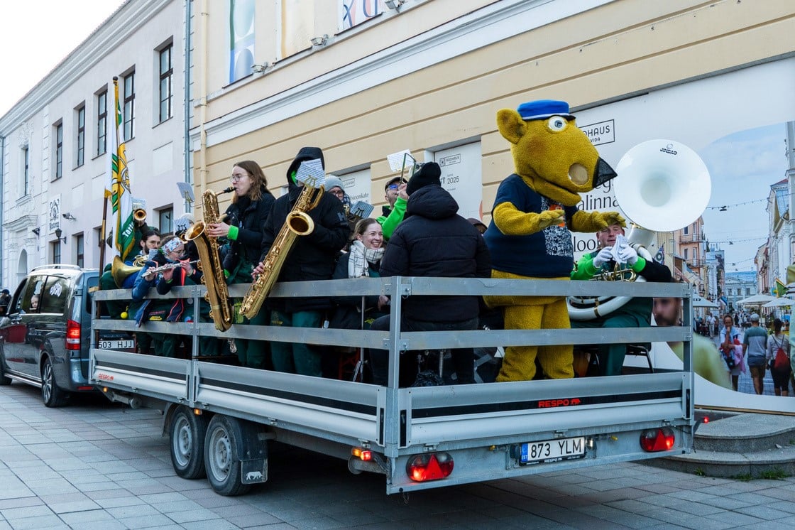 Tudengipäevade rongkäigu osalejad ja puhkpillimängijad sõidavad haagisel mööda Tartu kesklinna tänavat.