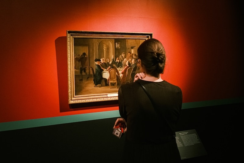 Külastaja vaatab punasel seinal eksponeeritud maali Tartu kunstimuuseumis