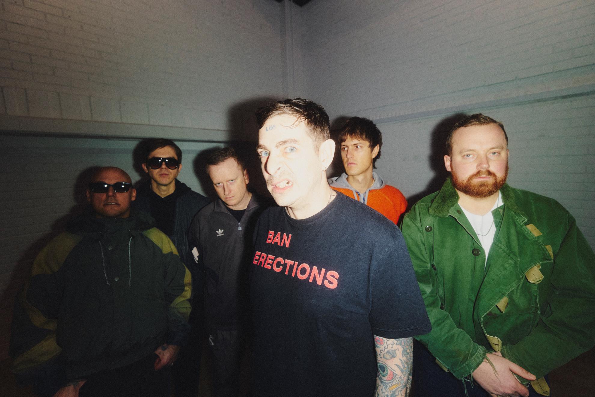 Bänd Viagra Boys poseerib koos – esiplaanil on laulja mustas T-särgis, ülejäänud liikmed seisavad tema taga hämaras ruumis