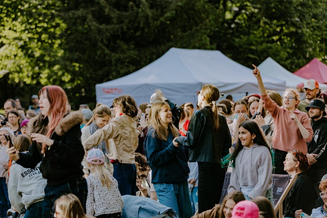 Lapsed, noored ja täiskasvanud osalevad päikeselisel väliüritusel Tartus, taustal valged telgid ja roheline pargiala.