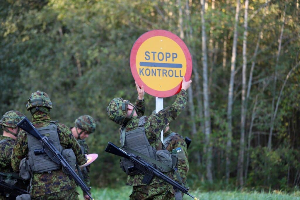 Sõjaväevormis õppusel osalejad paigaldavad metsatee äärde „Stopp kontroll“ märki