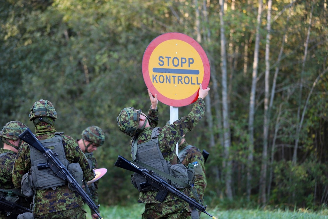 Sõjaväevormis õppusel osalejad paigaldavad metsatee äärde „Stopp kontroll“ märki