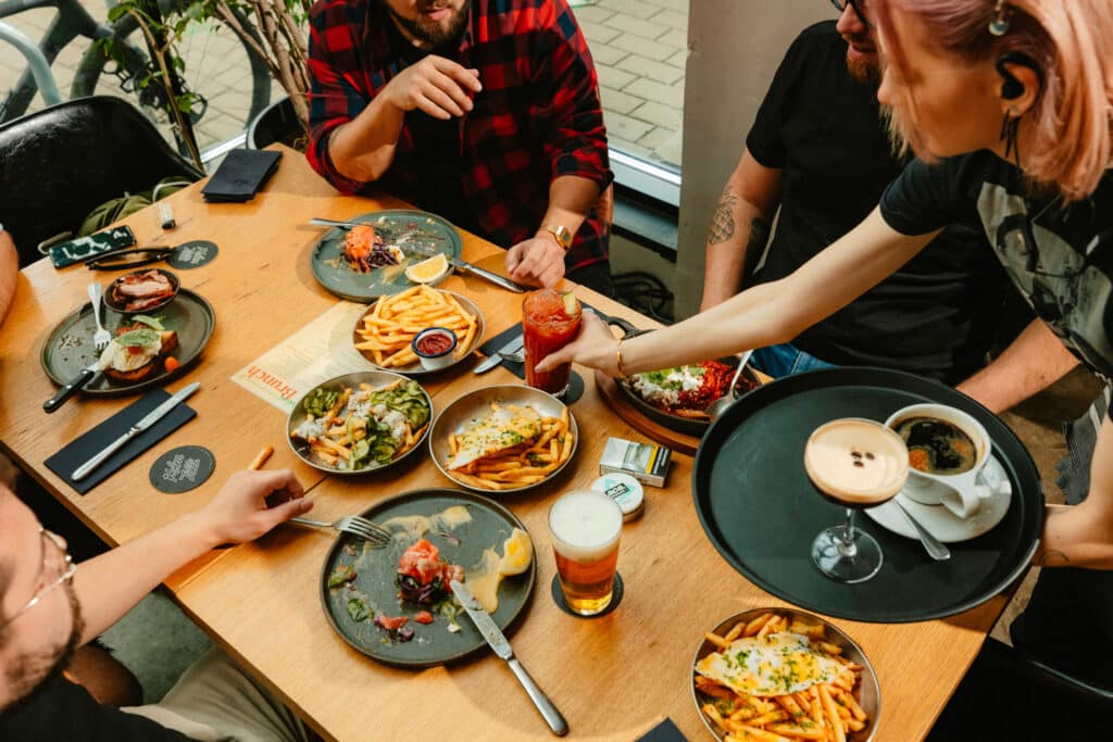 People dining at Kolm Tilli restaurant, with dishes, French fries, and drinks on the table.